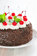 Chocolate cake with whipped cream and glazed cherries
