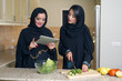 Two Young Arabian Women Checking Recipe on a mobile pad