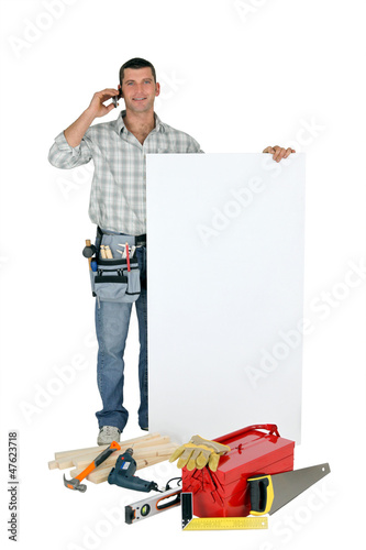 Photo: Handyman with a board left blank for your message Handyman with a board left blank for your message