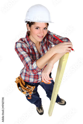 Photo: Female carpenter marking wood with pencil Female carpenter marking wood with pencil