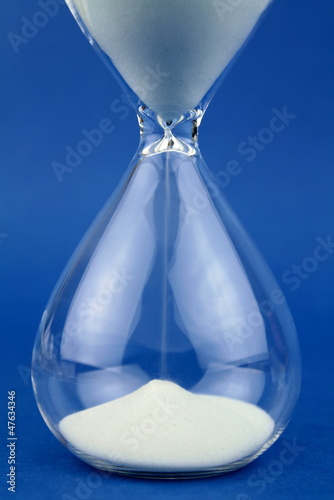 Photo: Close up hourglass on blue background. Close up hourglass on blue background.