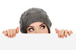Photo: Girl in knitted hat looking over white board Girl in knitted hat looking over white board