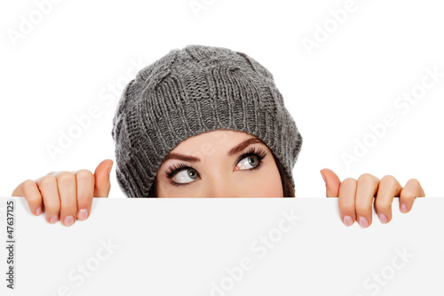 Photo: Girl in knitted hat looking over white board Girl in knitted hat looking over white board