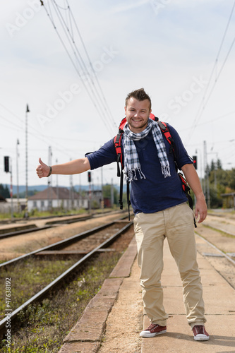 Photo: Man hitchhiking on railroad train station smiling Man hitchhiking on railroad train station smiling