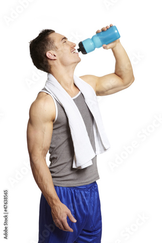 Photo: Muscular young man drinking in sports outfit Muscular young man drinking in sports outfit