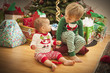 Baby and Young Boy Enjoying Christmas Morning Near The Tree