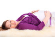 Photo: Pregnant woman lies on white fur and touches belly isolated Pregnant woman lies on white fur and touches belly isolated