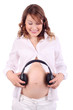 Pregnant woman in white holds headphones close to belly isolated