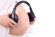 Hands of pregnant woman in white holding black headphones