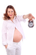 Pregnant woman in white holds at arm alarm clock isolated