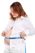 Pregnant woman in white measures stomach  by centimeter tape