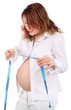 Pregnant woman in white looks at centimeter tape isolated