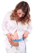 Smiling pregnant woman measures belly by blue centimeter
