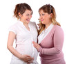 Pregnant woman in white and her girlfriend touching her stomach