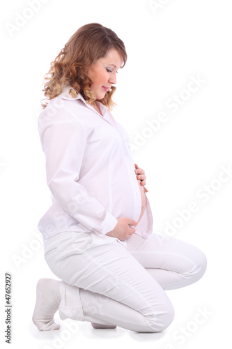 Photo: Smiling pregnant woman in white squats on haunches Smiling pregnant woman in white squats on haunches