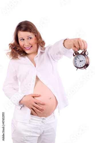 Photo: Pregnant woman in white holds at arm alarm clock Pregnant woman in white holds at arm alarm clock