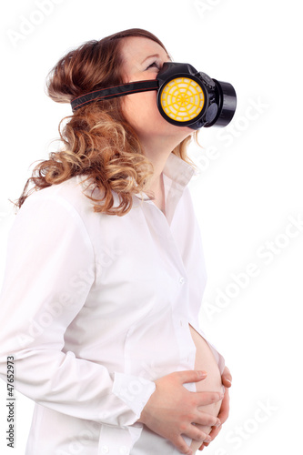 Photo: Pregnant suffering woman in white and respirator holds belly Pregnant suffering woman in white and respirator holds belly