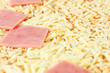 Close up of appetizing pizza with yellow cheese and pink ham.