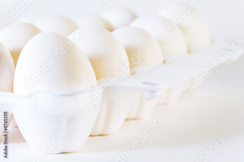 Photo: Close up of ten white eggs in white container on white Close up of ten white eggs in white container on white