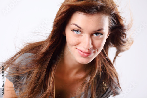 Photo: Beautiful young woman in grey dress with flowing hair smiles Beautiful young woman in grey dress with flowing hair smiles
