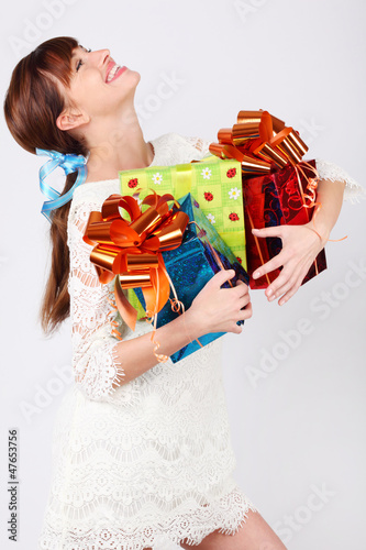 Photo: Laughing girl in white dress holds green, red and blue boxes Laughing girl in white dress holds green, red and blue boxes