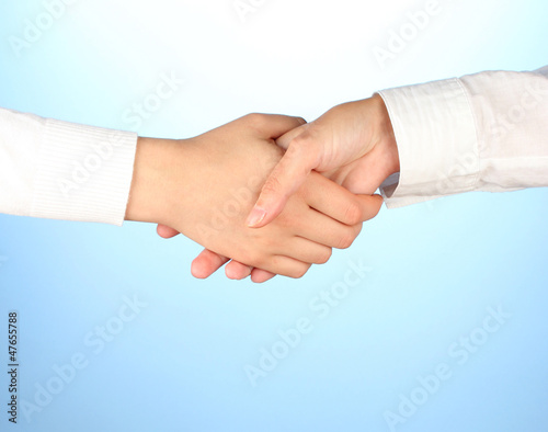 Photo: shaking hands after signing the agreement, on a blue background shaking hands after signing the agreement, on a blue background