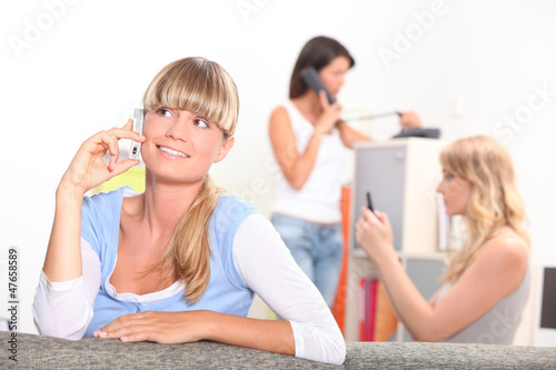 Photo: Three young women making calls Three young women making calls