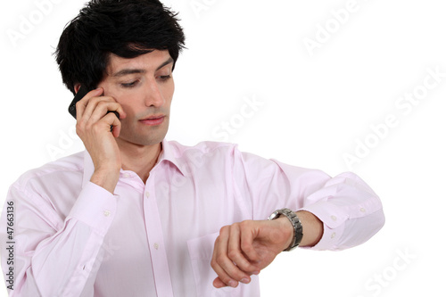Photo: man talking on his cell and watching his watch man talking on his cell and watching his watch