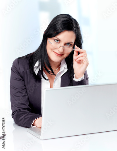 Photo: Competent business woman with laptop and a pair of glasses Competent business woman with laptop and a pair of glasses