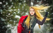 girl with cap and gloves playing with snow in the winter forest