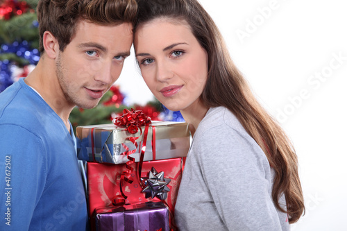 Photo: Young couple stood with pile of presents Young couple stood with pile of presents