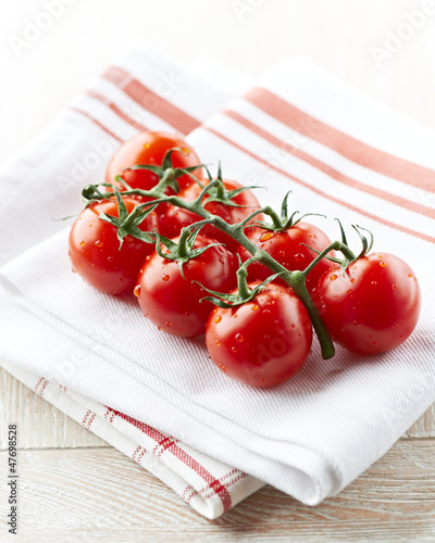 Photo: Fresh cherry tomatoes on kitchen towels Fresh cherry tomatoes on kitchen towels