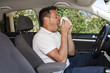 Man sneezing in car