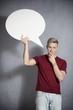 Pensive man holding white blank speech bubble.