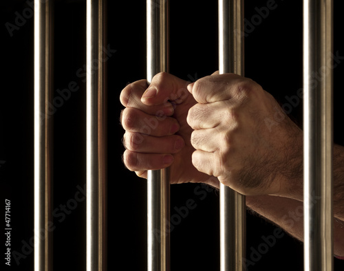 Photo: hands of a prisoner behind bars hands of a prisoner behind bars