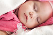 Baby girl sleeps with a pacifier nearby