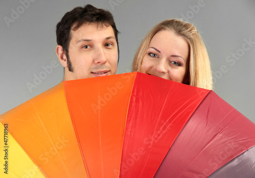 Photo: Loving couple with umbrella on grey background Loving couple with umbrella on grey background