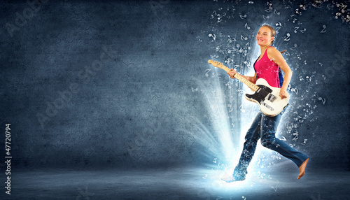 Photo: young woman playing on electro guitar and jumping young woman playing on electro guitar and jumping