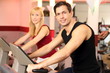 Attractive woman and a man cycling in a gym