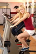 Attractive woman and a man cycling in a gym