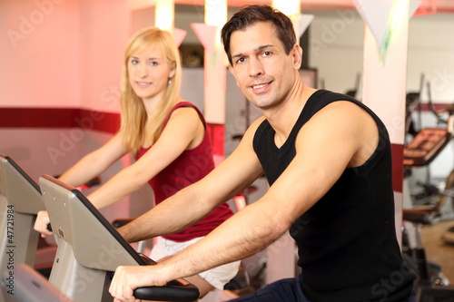 Photo: Attractive woman and a man cycling in a gym Attractive woman and a man cycling in a gym