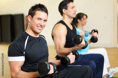 Photo: Group of three people training with gymnastic balls and dumbbell Group of three people training with gymnastic balls and dumbbell