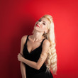 Beautiful blonde woman close up portrait against red background.