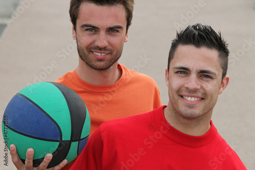 Photo: Two men playing basketball outdoors Two men playing basketball outdoors