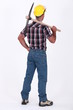 bricklayer seen from behind with pickaxe over his shoulder
