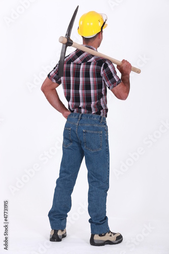 Photo: bricklayer seen from behind with pickaxe over his shoulder bricklayer seen from behind with pickaxe over his shoulder