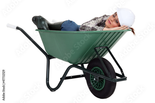 Photo: A female construction worker sleeping in a wheelbarrow. A female construction worker sleeping in a wheelbarrow.