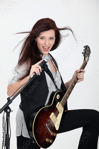 Photo: young woman playing guitar and singing young woman playing guitar and singing
