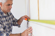 Grey haired handyman measuring wall