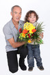 a grandfather and his little son holding a flowers bouquet